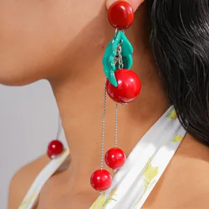 Detailed macro view showing the red cherry resin spheres and green leaves of these tassel earrings
