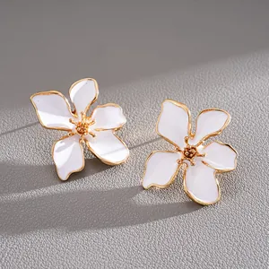 Primer plano de los elegantes pétalos de esmalte blanco y el centro dorado de los pendientes