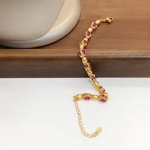Vue rapprochée détaillée d'un élégant bracelet doré orné de zircons rouges de forme ovale