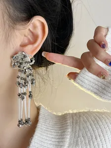 Detailed shot of vintage silver needle flower stud earrings with long beaded tassels