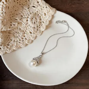 Detailed shot of an elegant fan-shaped zircon pearl necklace on a white ceramic plate