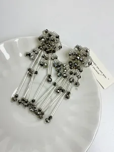 Close-up of elegant silver beaded flower tassel earrings displayed on a white plate.