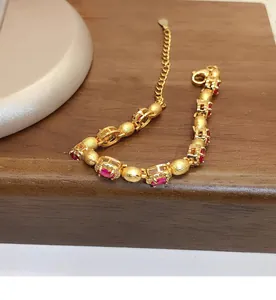 Vue détaillée d'un bracelet vintage en or avec des zircons rouges ovales et perles