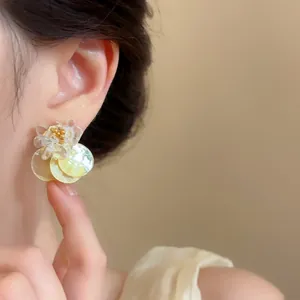 Close-up of elegant summer shell earrings with crushed stones on a model's ear
