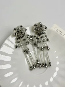 Close-up of elegant silver flower tassel earrings with intricate beadwork detailing