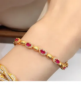 Vue détaillée d'un élégant bracelet doré avec zircons rouges ovales et micro-pavé