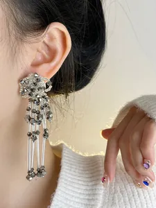 Close-up of silver beaded flower tassel earrings worn on ear with white sweater.