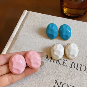 Macro view of textured acrylic oval stud earrings in pink, blue and white colors