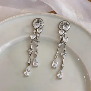 Gros plan de boucles d'oreilles à clips avec zircons en forme de cœur et goutte.
