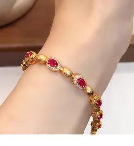 Gros plan d'un élégant bracelet doré avec zircons rouges ovales et cristaux blancs