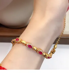 Détail d'un bracelet plaqué or avec des pierres de zircon rouges ovales