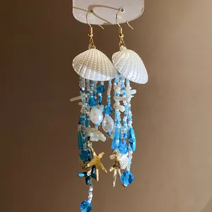 Vue détaillée de boucles d'oreilles en perles avec coquillages blancs et étoiles de mer