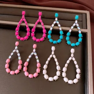 Vintage teardrop dangle earrings with colorful stones and crystal accents on a tray