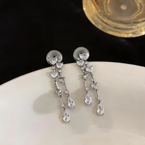 Vue détaillée de boucles d'oreilles à clip argentées avec zircons cœur et goutte.