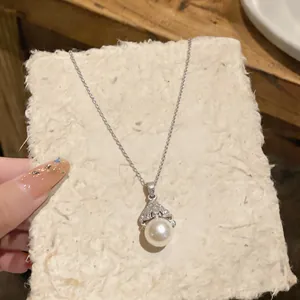 Close-up of elegant fan-shaped zircon pendant with round pearl on a silver chain necklace