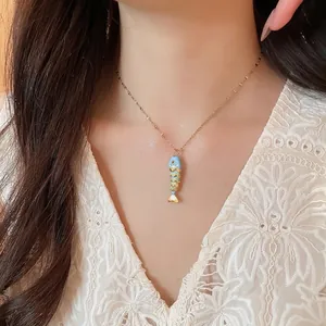 Chic gold-plated necklace featuring a vibrant colorful fish pendant, styled on a model.