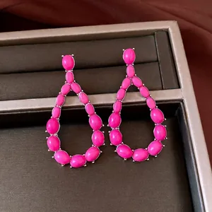 Vintage silver teardrop earrings with vibrant pink stones displayed on jewelry tray