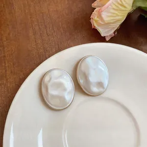 Detailed view of elegant white acrylic oval stud earrings with mother-of-pearl texture