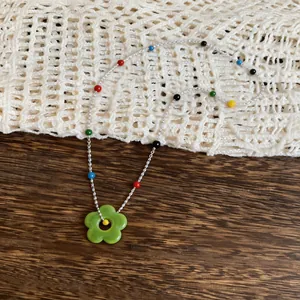 Detailed view of silver chain necklace with colorful beads and green flower pendant