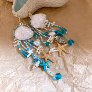 Gros plan détaillé de boucles d'oreilles en perles avec breloques coquillage et étoile
