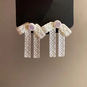 Elegant bow-shaped silver needle drop earrings featuring a delicate pink gemstone center.