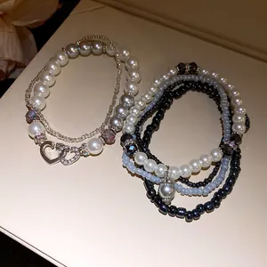 Dettaglio di braccialetti di perle bohémien a più strati con ciondolo a doppio cuore scintillante.