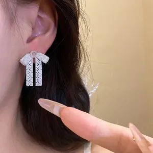 Elegant silver bow drop earrings with hollow texture on model's ear