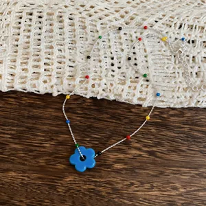 Macro view of a colorful dopamine style beaded necklace featuring a vibrant blue flower