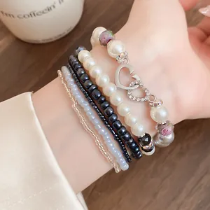 Vista dettagliata di un set di bracciali bohémien multistrato con perle e ciondoli a cuore