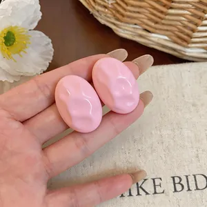 Close-up detail of light pink oval acrylic earrings with a unique textured surface