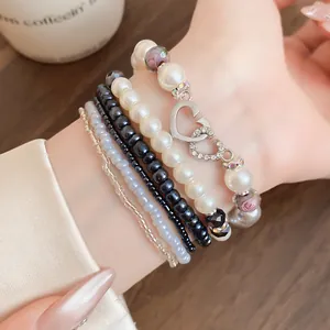 Dettaglio del set di braccialetti di perle multistrato con ciondoli a cuore