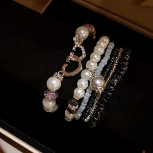 Vista dettagliata di un set di braccialetti di perle bohémien multistrato con ciondoli a cuore.