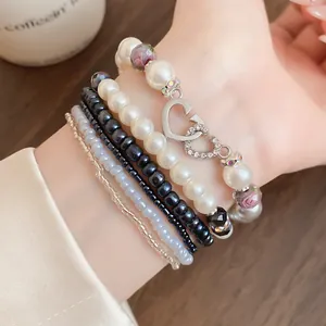 Vista dettagliata del set di bracciali bohémien a strati con perle, grani neri e ciondolo a cuore.