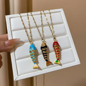 Detailed view of three colorful fish-shaped pendant necklaces on a white display tray