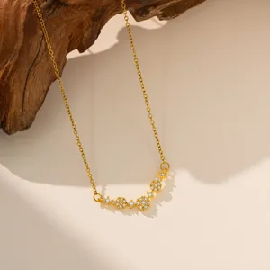 Elegante collar de acero de titanio dorado con flores de circón sobre fondo de madera natural