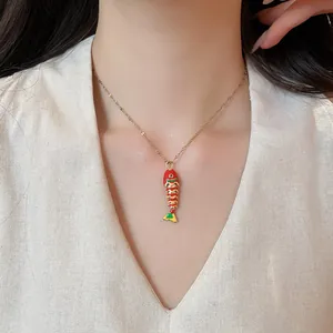 Detailed view of a fashionable red enamel fish pendant necklace on a model's neck.