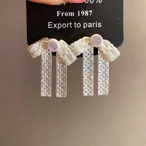 Close-up detail of silver bow stud earrings with pink beads on display card