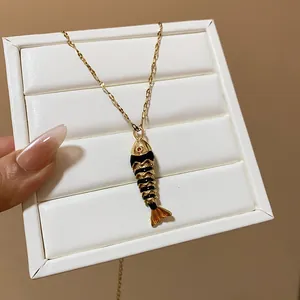 Detailed macro view of a unique gold-toned fish pendant featuring black enamel and red eye