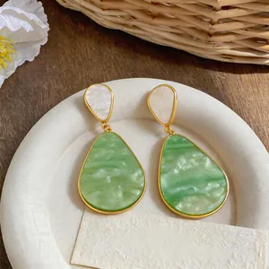 Dettaglio dei pendenti in resina verde effetto marmo con raffinata finitura dorata.