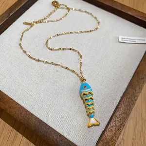 Detailed view of an elegant gold necklace featuring a colorful enamel fish bone pendant
