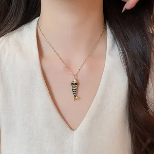 Close-up detail of a colorful fish pendant necklace with gold chain worn by model
