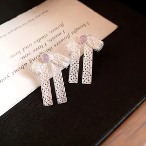 Detailed macro view of silver bow-knot earrings featuring elegant lavender beads