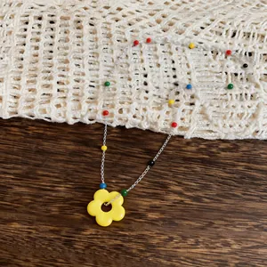Detailed macro shot of a vibrant yellow flower pendant on a colorful beaded chain.