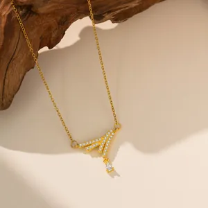 Detalle de collar de acero de titanio dorado con un colgante geométrico de circonitas.