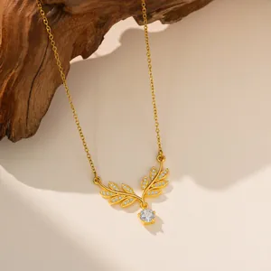 Detalle de collar de acero de titanio dorado con colgante de hoja de circonita y cristal