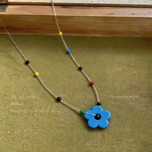 Close-up of dopamine style necklace featuring a blue flower pendant and colorful beads