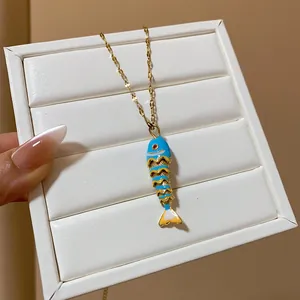 Close-up of a colorful enameled fish pendant necklace with a delicate gold chain.