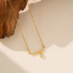 Primer plano de collar dorado con colgante de circonita brillante sobre madera