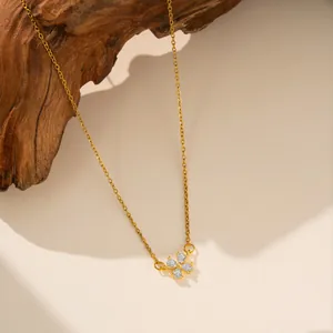 Detalle de collar de acero inoxidable dorado con colgante de flor de circón en madera.