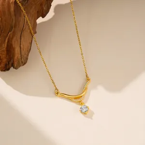 Primer plano de collar de acero de titanio dorado con colgante de circón curvo fino